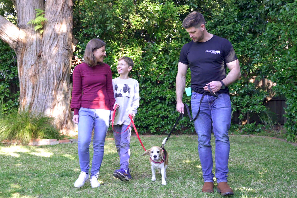 A boy and his mum walking a beagle alongside the clinician in a sunny garden