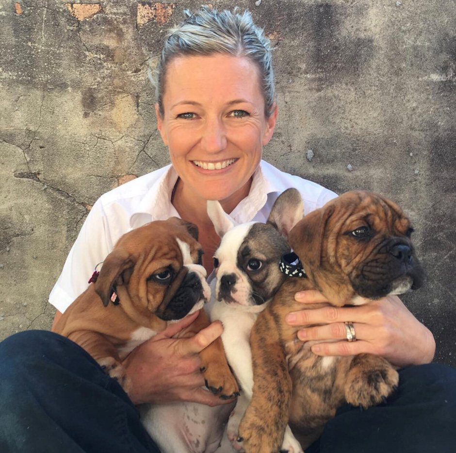 Amy Smith holding three bulldog puppies