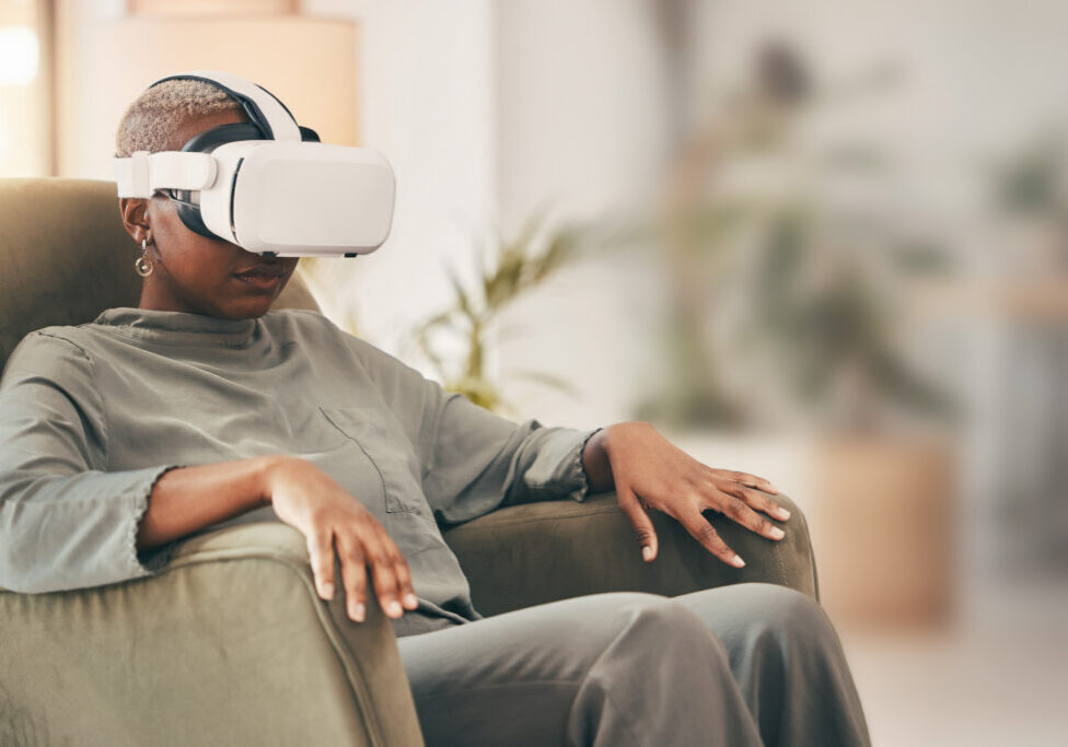 A woman sitting in an armchair wearing a virtual reality headset.